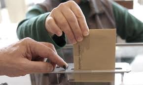 na fotografii urna wyborcza i ręka osoby wrzucającej swój głos